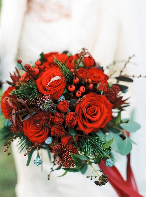amazing christmas wedding bouquet of red blooms berries greenery and fir branches