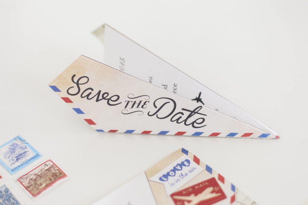 air mail style envelope for a save the date folded into a paper airplane