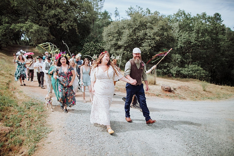 Un hombre y una mujer seguidos de un desfile de baile con la canción de entrada a su boda.